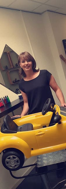 Linda bij de gele speelgoedauto waarin de kleinsten geknipt worden.